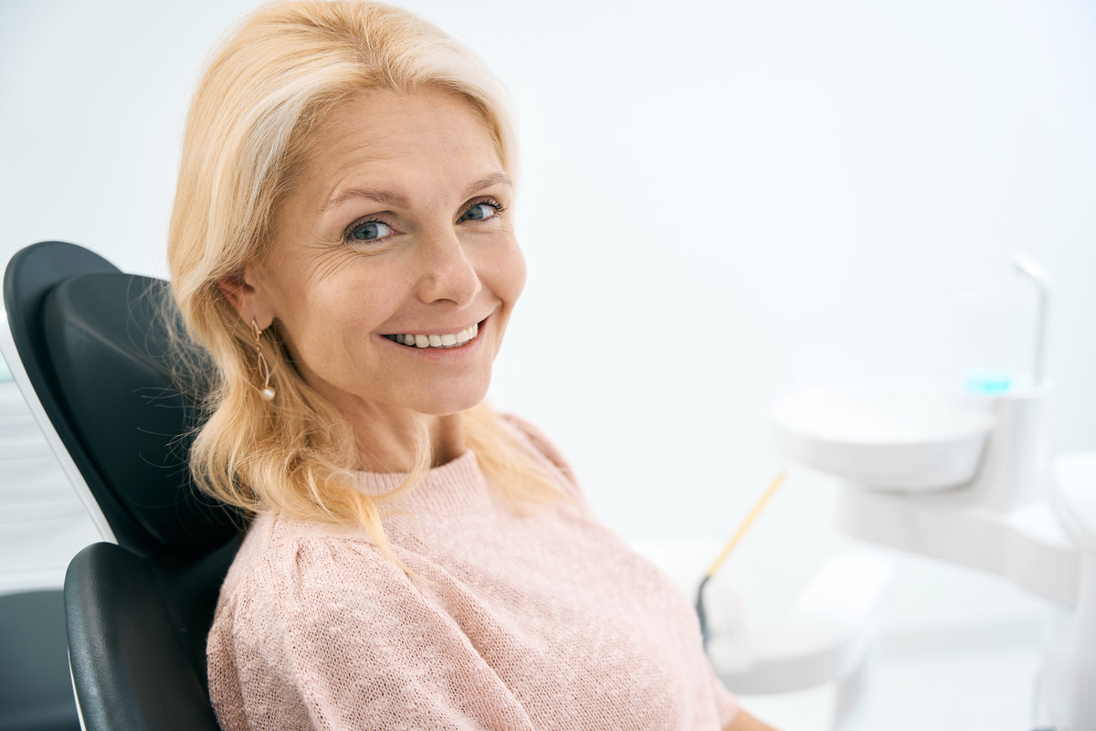 Portrait of happy woman sitting at dental chair and waiting for procedure